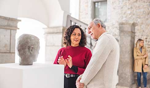 A museum expert speaks to a visitor about a statue 