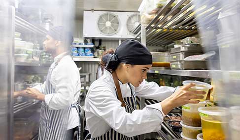 A cook browses through a walk-in fridge